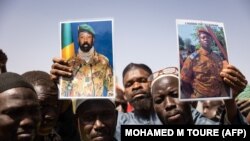 FILE — Protestors hold pictures of Col. Aissimi Goita, Mali's interim President, and of Lt. Col. Paul-Henri Sandaogo Damiba, Burkina Faso's interim President. Both leaders came to power after a military coup.