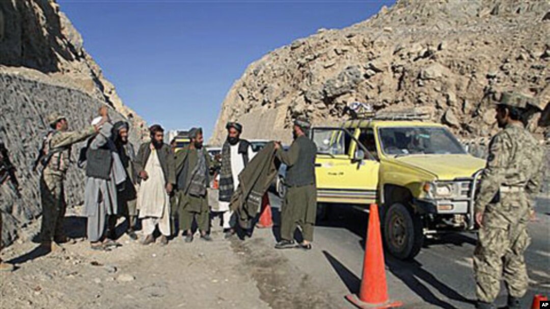 An Afghan policeman, left, searches men at a check point in Kandahar, 12 Dec, 2010