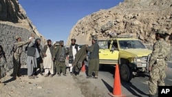 An Afghan policeman, left, searches men at a check point in Kandahar, 12 Dec, 2010