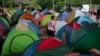 ARCHIVO - Un migrante que cruzó a pie el Tapón del Darién desde Colombia, camina entre tiendas de campaña en un campamento temporal en Lajas Blancas, Panamá, el 28 de junio de 2024. 