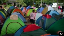 ARCHIVO - Un migrante que cruzó a pie el Tapón del Darién desde Colombia, camina entre tiendas de campaña en un campamento temporal en Lajas Blancas, Panamá, el 28 de junio de 2024. 