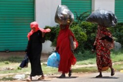 Sudanese women carry on their heads big bags of empty plastic bottles, as they walk on the street, in Khartoum, Sudan, June 15, 2019.