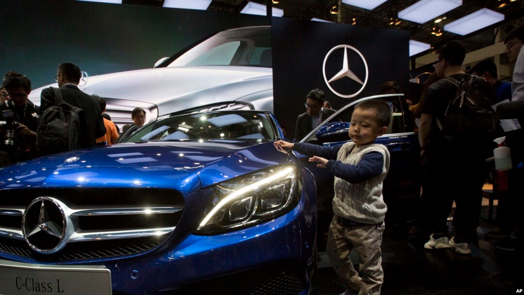 Chinese regulators have launched a series of anti-monopoly investigations of foreign automakers. In this photo taken Sunday, April 20, 2014, a child touches the latest model from Mercedes at an auto show in Beijing.