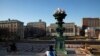 FILE - A woman sits on the near-empty campus at Columbia University in New York, March 9, 2020.