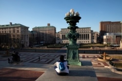 A woman sits on the Columbia University campus in New York, March 9, 2020.