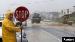 Loaders move tons of sand pushed by strong winds and rain onto a coastal road in Sydney's beachside suburb of Cronulla, April 21, 2015. 