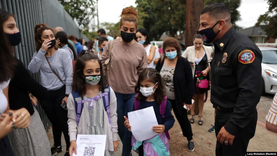 Nicole Tschabourian, 8, (kiri) dan Leah Yousefi, 8, tiba dengan barcode tercetak untuk hari pertama sekolah dan kembali ke pembelajaran tatap muka penuh waktu setelah jeda COVID-19, di Glendale, Los Angeles, California, AS, 18 Agustus 2021. (Foto: Reuters)