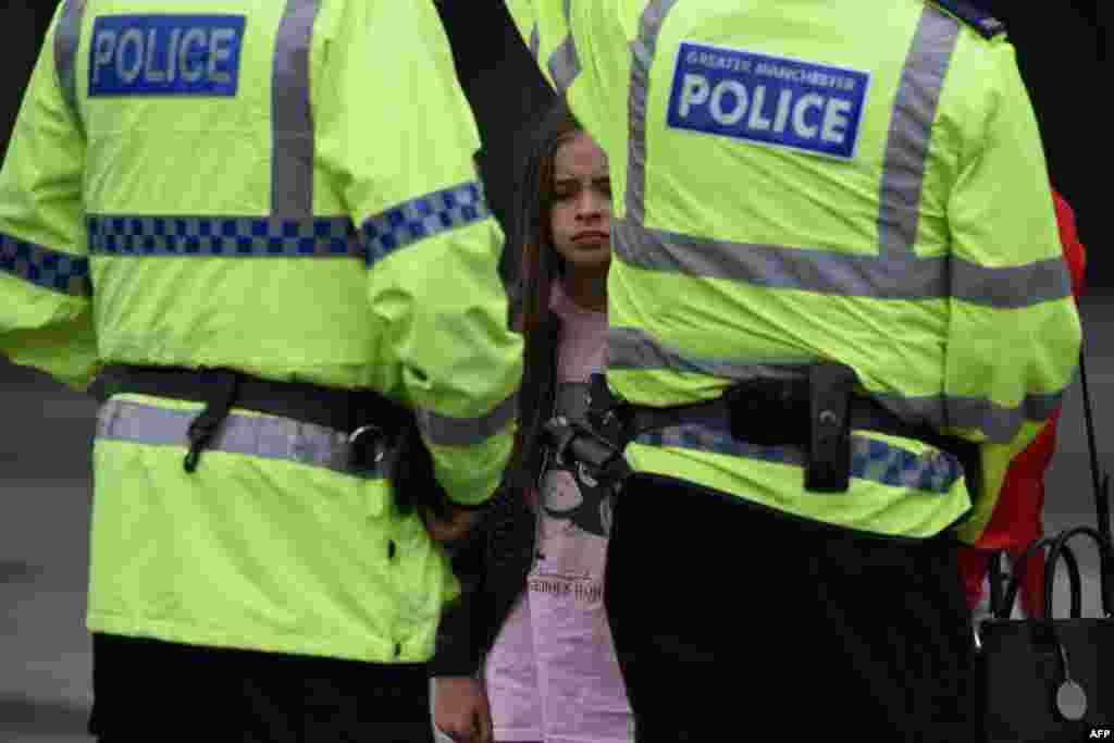 A woman and a young girl wearing a t-shirt of US singer Ariana Grande talks to police near Manchester Arena following a deadly terror attack in Manchester, northwest England on May 23, 2017.