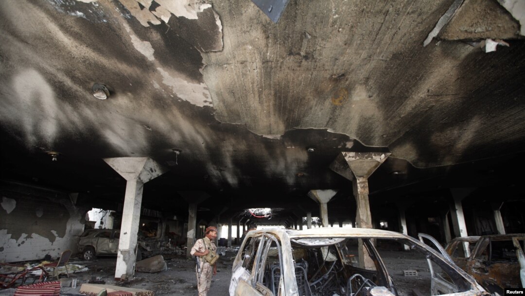 FILE - A security guard looks at a damaged car during a visit by human rights activists to a community hall that was struck by an airstrike during a funeral on October 8, in Sanaa, Yemen, Oct. 16, 2016. 