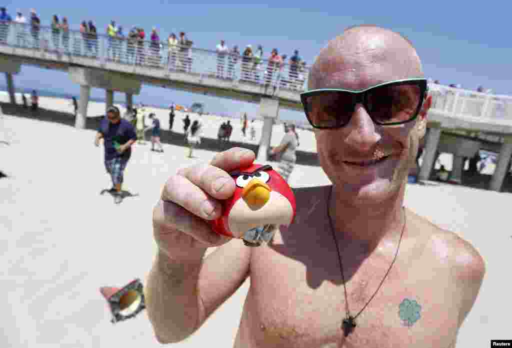 Brian Fitzpatrick holds a plastic Angry Bird orb filled with cash that he found in Hermosa Beach, California, May 31, 2014. An anonymous cash donor, who touched off a treasure hunt across San Francisco by hiding envelopes full of bills in unlikely places and providing clues via Twitter under the handle @HiddenCash, has moved operations to Los Angeles, sparking a frenzy with the first money drop.