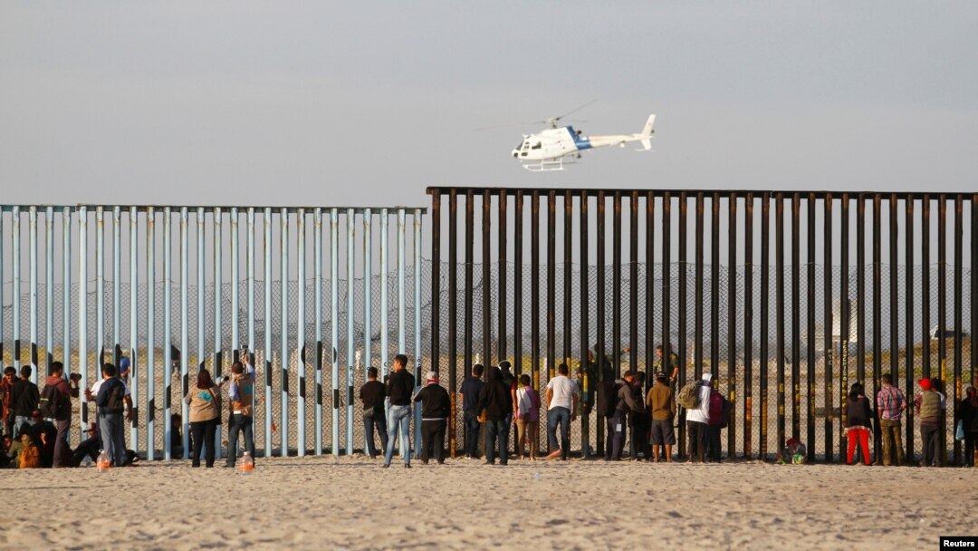Migran, bagian dari ribuan kafilah yang berusaha mencapai AS, melihat melalui pagar perbatasan antara Meksiko dan Amerika Serikat setibanya di Tijuana, Meksiko, 13 November 2018.