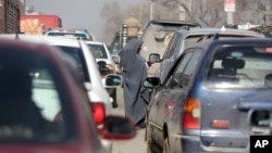 An Afghan woman asks for alms from driver on a street in Kabul, Afghanistan, Jan. 27, 2016.