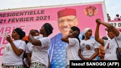 Des partisans dansent à côté d'une affiche du candidat à la présidence du Niger, Mohamed Bazoum, le 18 février 2021 à Niamey, avant le second tour de l'élection présidentielle du Niger le 21 février.
