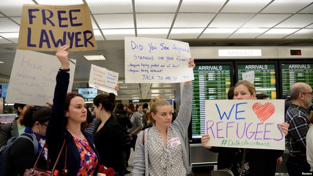 Lawyers offer free counseling as they join dozens of pro-immigration demonstrators cheering and holding signs as international passengers arrive at Dulles International Airport to protest President Donald Trump's travel ban in suburban Washington, Jan. 29, 2017.