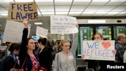 FILE - Lawyers offer free counseling as they join dozens of pro-immigration demonstrators cheering and holding signs as international passengers arrive at Dulles International Airport to protest President Donald Trump's travel ban in suburban Washington, Jan. 29, 2017.