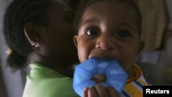 A mother who is infected with HIV holds her 10 month-old baby girl who is free from HIV infection. (Reuters/Oka Barta Daud)