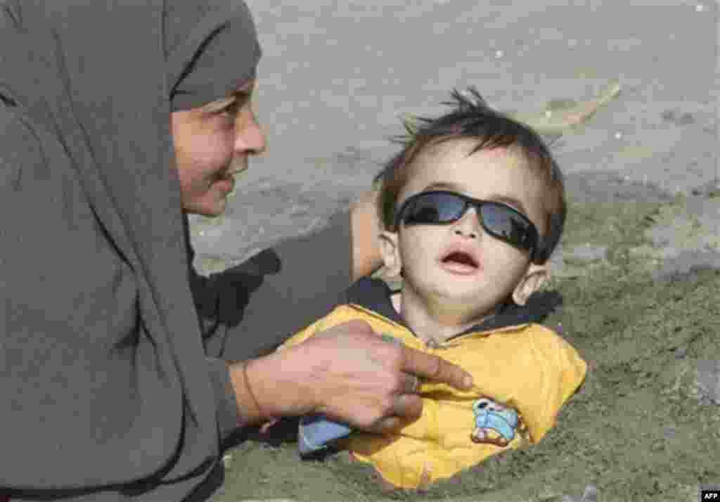 A Pakistani mother buries her child in mud during the solar eclipse in Karachi, Pakistan on Tuesday, Jan. 4, 2011. Superstitious people hope that burying ailing person during solar eclipse will cure them. (AP Photo/Fareed Khan)