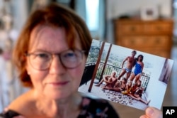 Claudia Huth, who lived in the West when Germany was divided, shows an old photo of her family and herself in her house in Egelsbach, Germany, on Oct. 31, 2024.