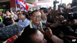 FILE - Sam Rainsy, center, leader of the opposition Cambodia National Rescue Party (CNRP), talks to journalists upon his arrival at Phnom Penh International Airport in Phnom Penh, Cambodia, Aug. 16, 2015. (AP Photo/Heng Sinith)