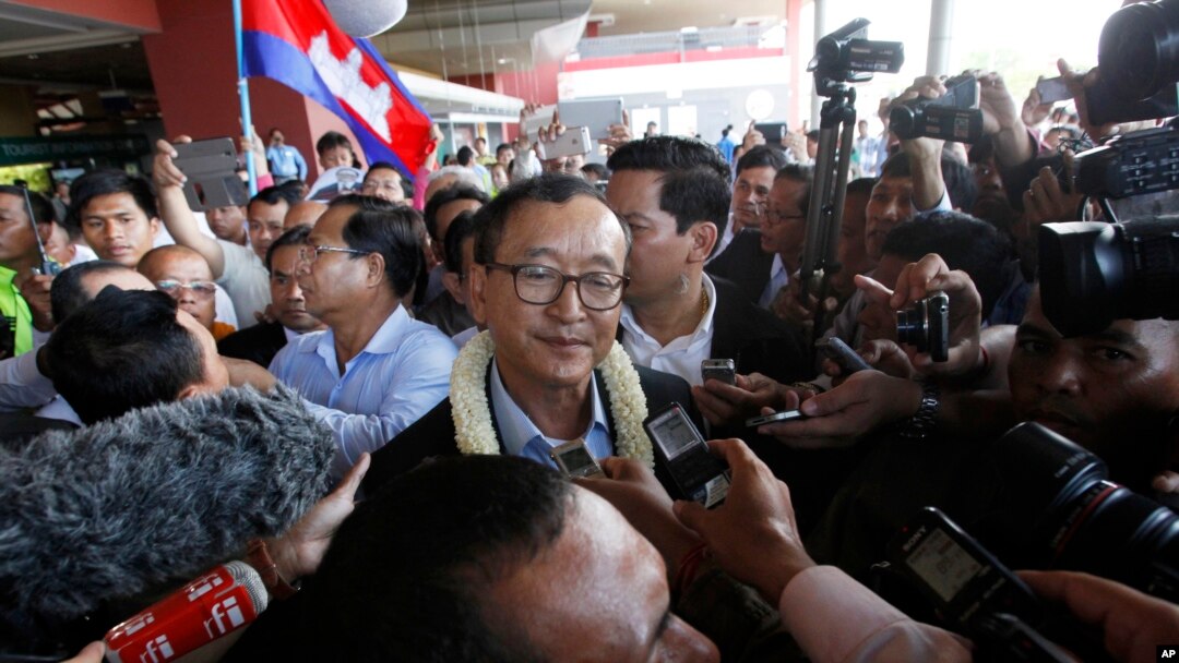 FILE - Sam Rainsy, center, leader of the opposition Cambodia National Rescue Party (CNRP), talks to journalists upon his arrival at Phnom Penh International Airport in Phnom Penh, Cambodia, Aug. 16, 2015.