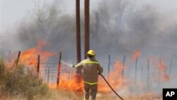 A volunteer firefighter fights a fire which began outside Marfa, Texas, and was carried by winds to nearby Fort Davis, April 9, 2011