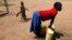 FILE- A girl prepares to lift a jerry can of water onto her head in the village of Loro in the Oyam district of northern Uganda. 