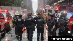 New York City police and firefighters arrive at the scene after a helicopter crashed atop a building in New York, June 10, 2019.