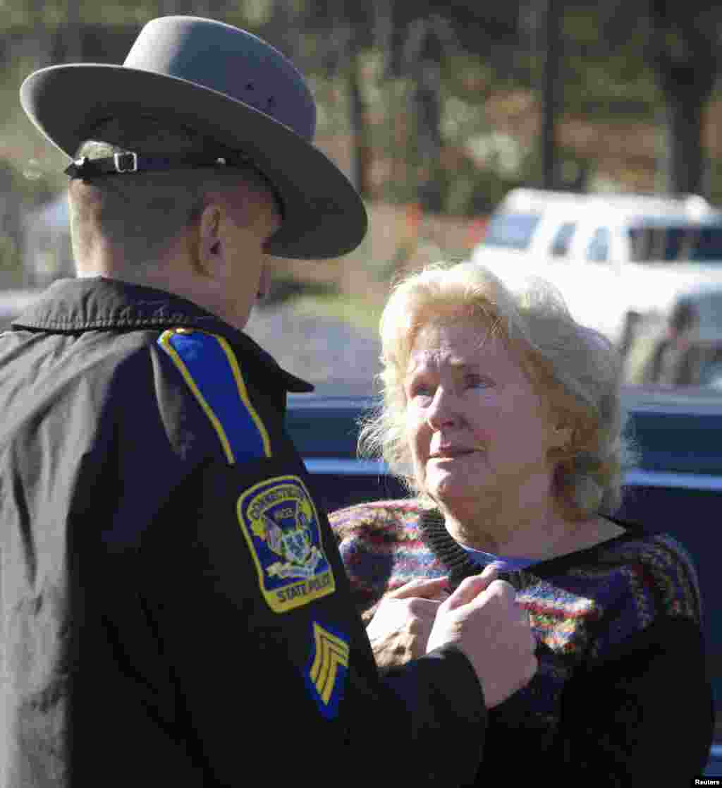 Una mujer conversa con un oficial de la Patrulla Estatal de Connecticut en busca de noticias sobre el tiroteo en la escuela, en Newtown, Connecticut. 