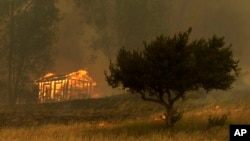 Fire engulfs a structure during a wildfire May 15, 2014, in Escondido, California.