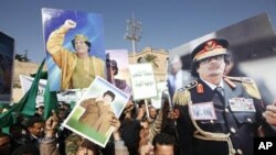 Supporters of Libyan leader Moammar Gadhafi hold his pictures as they take part in a pro-government rally in Tripoli, February 17, 2011