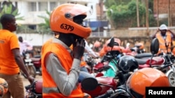 FILE - A motorcycle taxi driver known as boda-boda, from SafeBoda network, waits for a customer along a street in Kampala, Uganda, Oct. 5, 2018.