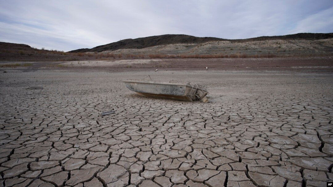 FILE - A formerly sunken boat sits on cracked earth scores of meters from the shoreline of Lake Mead at the Lake Mead National Recreation Area on May 10, 2022, near Boulder City, Nev. 