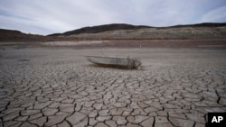 FILE - A formerly sunken boat sits on cracked earth scores of meters from the shoreline of Lake Mead at the Lake Mead National Recreation Area on May 10, 2022, near Boulder City, Nev. 