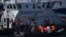 Pejabat Pasukan Perbatasan Inggris memindahkan migran yang dicegat saat bepergian dengan RIB dari Perancis ke Dover, Inggris tenggara pada 13 Agustus 2021. (Foto: AFP)