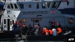 Pejabat Pasukan Perbatasan Inggris memindahkan migran yang dicegat saat bepergian dengan RIB dari Prancis ke Dover, Inggris tenggara pada 13 Agustus 2020. (Foto: AFP)