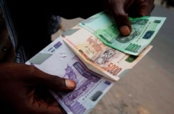 FILE - A trader displays Congolese currency bills on a street in Kinshasa, Democratic Republic of Congo, July 3, 2012.