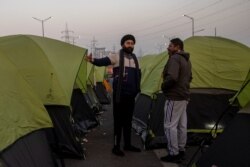 Farmers stand outside their tents at the site of a protest against new farm laws, at the Delhi-Uttar Pradesh border in Ghaziabad, India, Jan. 11, 2021.