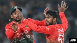 Bangladesh's Mehidy Hasan Miraz celebrates with his captain Najmul Hossain Shanto (L) after taking the wicket of India's Sanju Samson during the first Twenty20 cricket match between India and Bangladesh at the Shrimant Madhavrao Scindia Cricket Stadium in