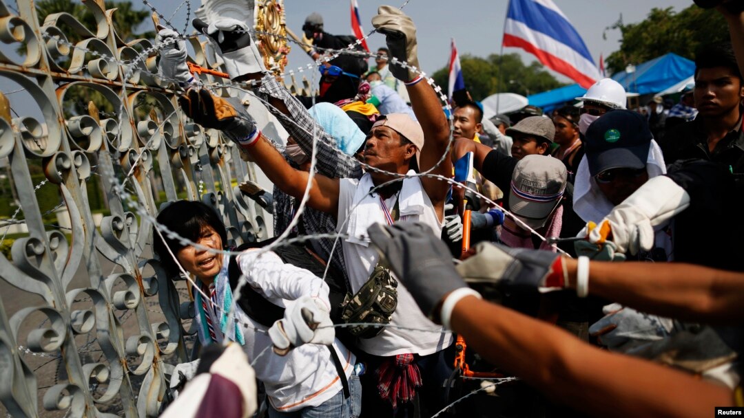 Para demonstran anti pemerintah memotong kawat berduri, sementara sebagian kecil dari mereka memasuki komplek kantor PM Thailand dan memutuskan aliran listriknya, Kamis (12/12). 