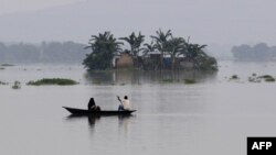 Indian villagers paddle a boat through floodwaters near partially submerged houses in Balimukh village in the Morigaon district of Assam state, Aug. 17, 2014. 