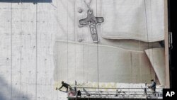 Pintores trabajan en un mural del papa Francisco en el costado de un edificio en la esquina de la calle 34 y la 8a. Avenida, en Nueva York.