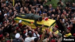 FILE - A member of Hezbollah mourns as he lies on top of the coffin of Hezbollah member Jaafar Serhan, during his funeral in Mashghara, Lebanon November 13, 2023.