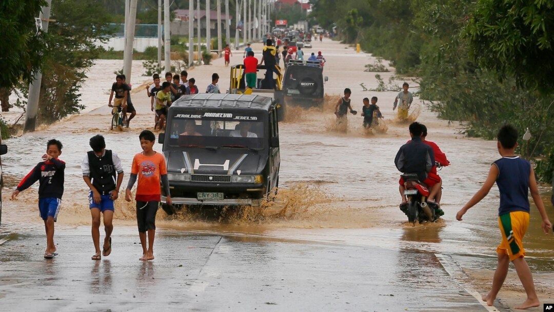 Warga menyeberang melaui banjir yang disebabkan oleh topan Koppu di kota Zaragosa, provinsi Nueva Ecija, Manila Utara, Filipina (19/10). 