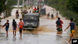 Warga menyeberang melaui banjir yang disebabkan oleh topan Koppu di kota Zaragosa, provinsi Nueva Ecija, Manila Utara, Filipina (19/10). 