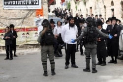 FILE - In this March 30, 2020, photo, ultra-Orthodox Jews gather during a protest against government's measures to stop the spread of the coronavirus in the Orthodox neighborhood of Mea Shearim in Jerusalem.