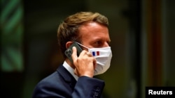 Presiden Prancis Emmanuel Macron berbicara di telepon selama pertemuan tatap muka pertama UE sejak wabah COVID-19, di Brussel, Belgia 20 Juli 2020. (Foto: John Thys via REUTERS)