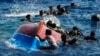 Migranti plivaju pored prevrnutog drvenog čamca tokom spasilačke operacije španske nevladine organizacije Open Arms na jugu italijanskog ostrva Lampeduza u Sredozemnom moru, 11. avgusta 2022.