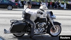 FILE - Jeremiah Gerbracht, a retired dog trainer, rides his Harley Davidson motorcycle with his dog on Wilshire Boulevard in Los Angeles, California.