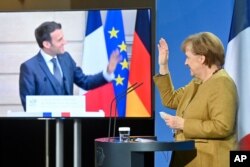 FILE - German Chancellor Angela Merkel waves to French President Emmanuel Macron at the end of a press conference following German-French Security Council video talks in Berlin, Germany, Feb. 5, 2021.