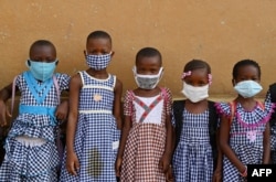 FILE - Children wearing face masks gather outside their classroom at a school in Attecoube, popular district of Abidjan, Ivory Coast, May 25, 2020.